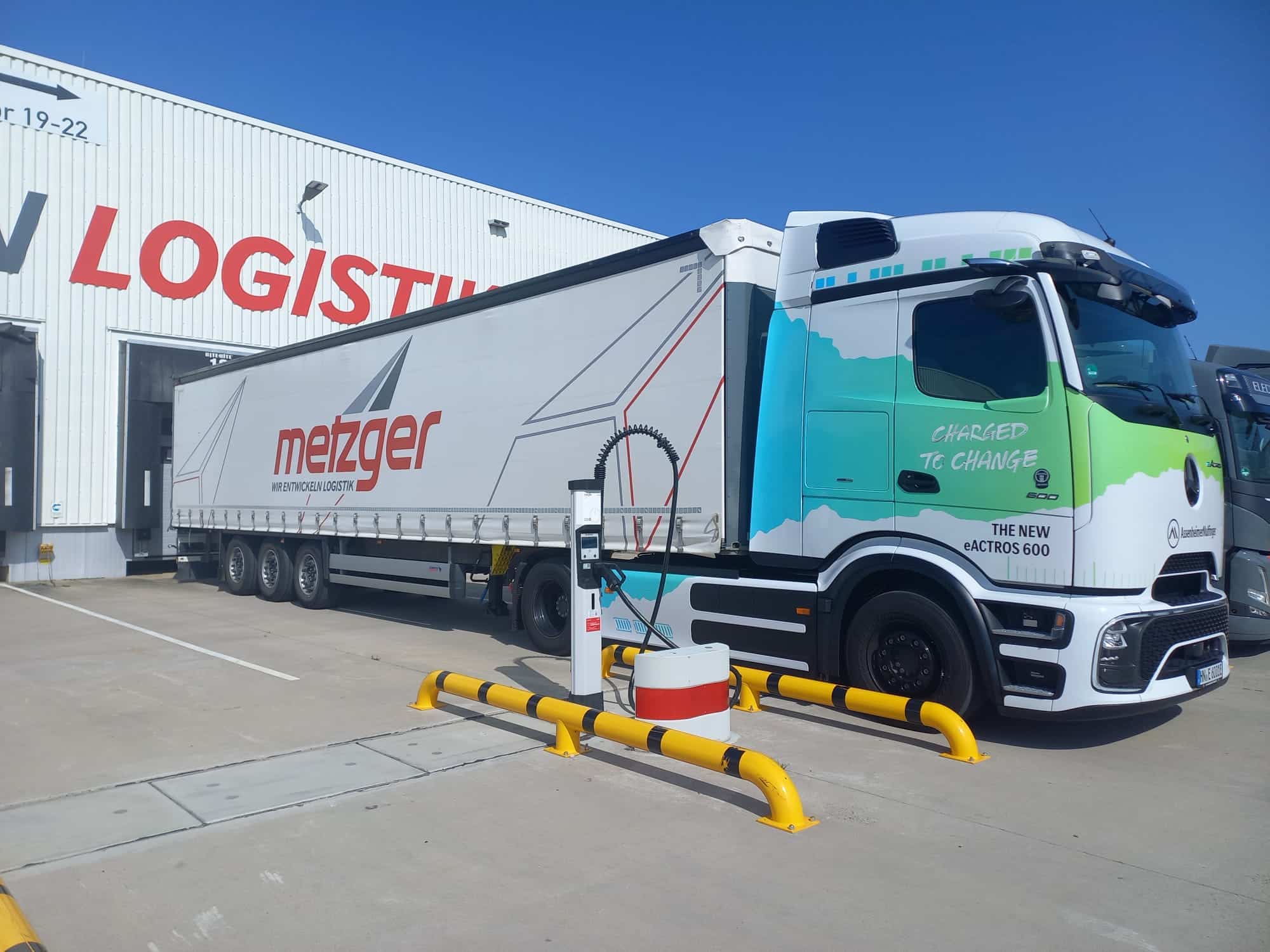 Elektro-Lkw lädt an Ladesäule vor Logistikzentrum