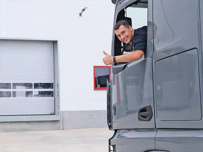 Lkw-Fahrer zeigt Daumen hoch aus Fahrerhaus