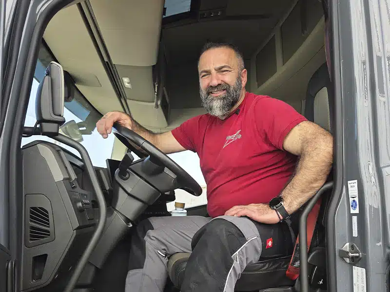 Bärtiger Mann sitzt lächelnd im LKW-Fahrerhaus