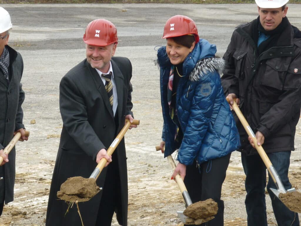 Spatenstich mit Schutzhelmen auf Baustelle