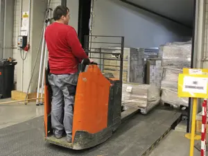 Arbeiter mit Hubwagen lädt Paletten im Lager